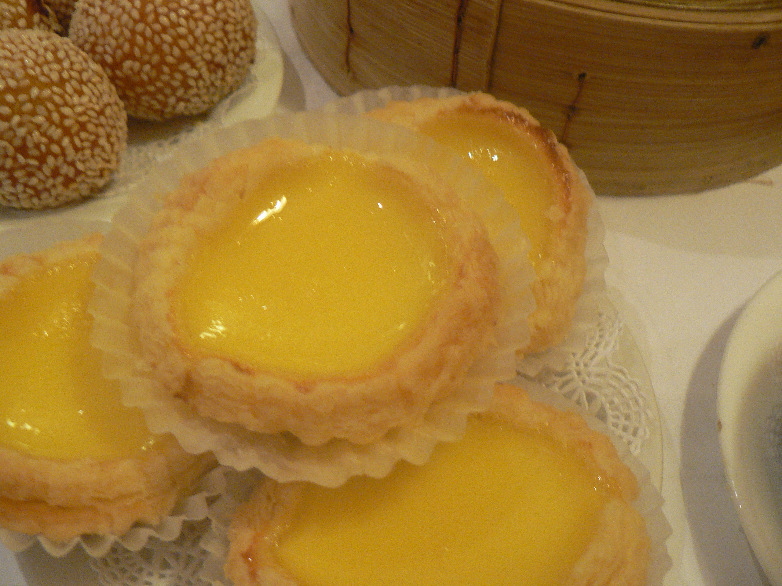 Four egg custard tarts; the first one is on top of the others.