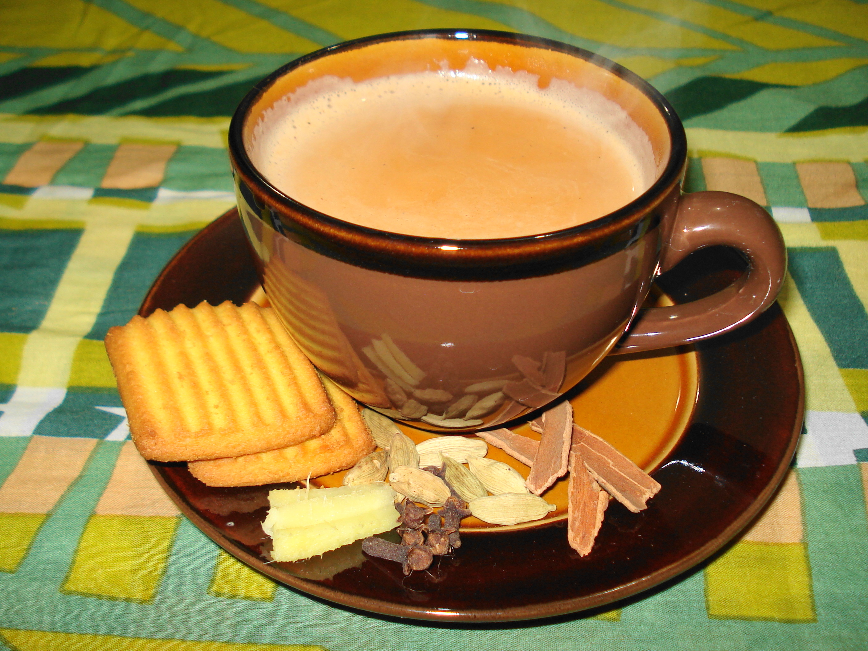 Masala chai served in a cup, pictured with a rusk.